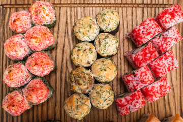 Different types of delicious and juicy sushi and rolls on a wooden board