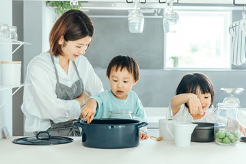 綺麗なお家のキッチンでお母さんが子供たちに料理を教えている姿　子育て　教育　mother kids