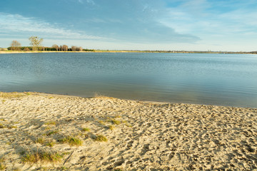 Empty sandy beach by the lake and a cloud in the sky