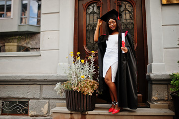 Young female african american student with diploma poses outdoors.