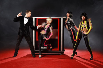 Magician performer and beauty girls show trick with box illusion on the ring in circus