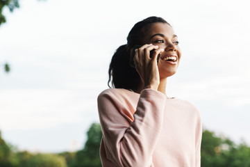 Image of african american girl talking on mobile phone while walking