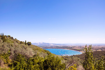 View on the Golfo di Baratti bay on Piombino peninsula from Populonia village. Turquoise water of the sea, marina with boats, italian costal landscape in summer.