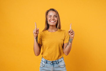 Image of blonde joyful woman winking and pointing fingers upward