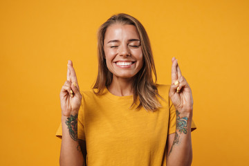 Image of blonde excited woman holding fingers crossed for good luck