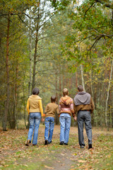 Family of four walking in autumn forest
