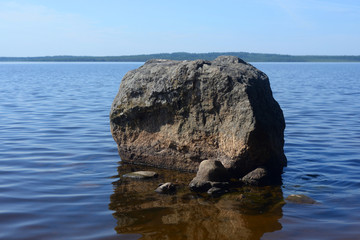 Large granite boulder on coast of lake.