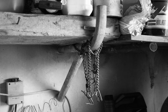 Es una foto en blanco y negro de unas cadenas colgadas de un tubo, en la estanter&iacute;a de arriba y productos para las piscinas , como cloro en pastillas