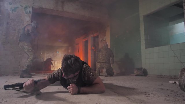 Injured military man crawling on his belly on durty floor of smoky ruined building trying to leave place of shelling. Strong-willed wounded army male saving his life during shootout