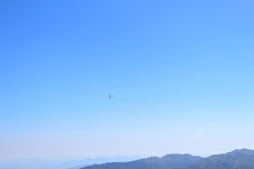 Fototapeta na wymiar An ultralight aircraft glides over the summit of Mount Cimone at 2,165 meters above sea level on the Modenese Apennines