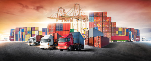 Business logistics and transportation concept of containers box from cargo freight ship with working crane bridge in shipyard at sunset sky, logistic import export and transport industry background