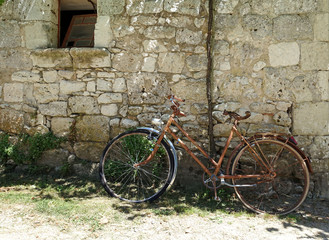 Fototapeta na wymiar old abandoned bike leaning against a stone wall