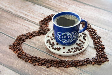 coffee drink in a mug and black coffee beans in a heart shape