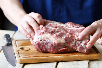 Selective focus. Raw meat in the hands of the chef. Preparing meat for barbecue. Pork neck.