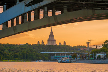 Bridge over the river in the sunset rays in Moscow, behind which you can see the famous high-rise