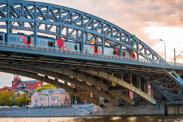 Bridge over the river in the sunset rays in Moscow, on which the train moves
