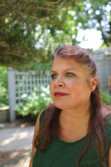 Happy smiling woman in green dress sitting in garden.