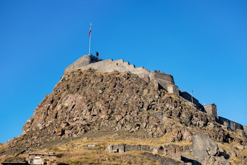 Main building & heart of Kars Castle - its citadel. It was founded in 1153 on almost unassailable rock. Near flag are portrait of Ataturk & writing in Turkish 'Motherland remembers you'