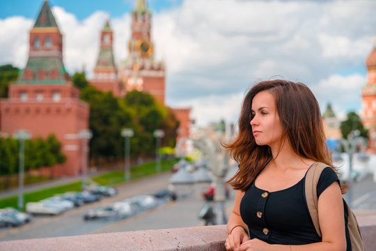 A charming young woman stands on a bridge with a background on the Kremlin in Moscow, Russia's main attraction