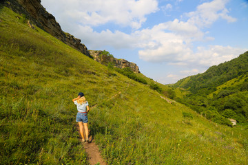 Woman traveller with stretched arms standing at the top of the hill in Caucasus mountains Russia. Happy girl hiker in the mountains.