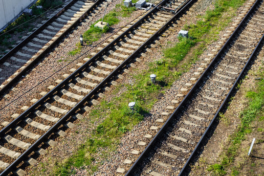 Metal railroad tracks diverging in different directions. Grass & gravel are filling space between rails
