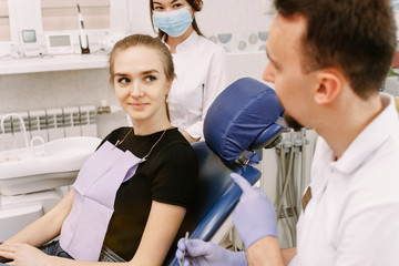 Dentist talking to a patient. Nearby is the dentists assistant. Reception in the dentists office and dental treatment