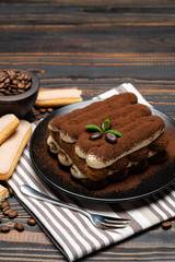 Classic tiramisu dessert on ceramic plate on wooden background