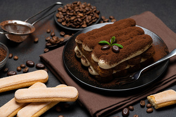 Classic tiramisu dessert and savoiardi cookies on ceramic plate on concrete background