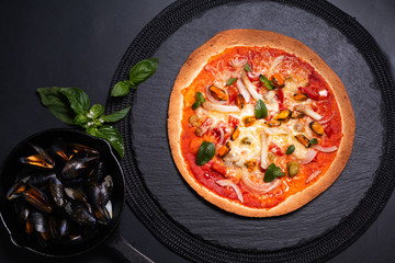Food concept Homemade Tortilla Seafood pizza on black slate stone plate on black background with copy space