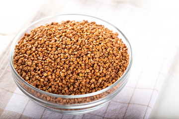 Bowl of raw buckwheat on wooden background. Buckwheat groats (hulled seeds) in bowl.