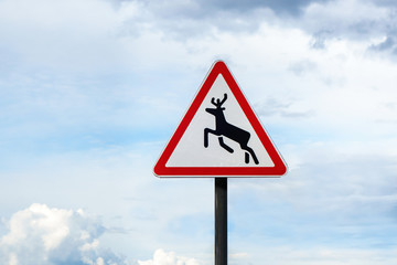 International traffic warning sign 'Wild animals' on cloudy sky background