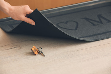 Woman putting spare key under door mat