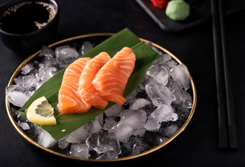 salmon sashimi on ice in a black plate