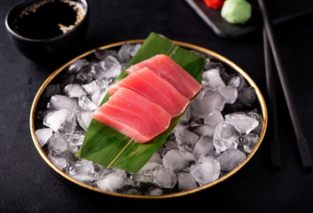 tuna sashimi on ice in a black plate