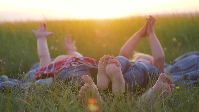 Two happy children, a boy and a girl, lie on the green grass on a summer day. Hands close up.