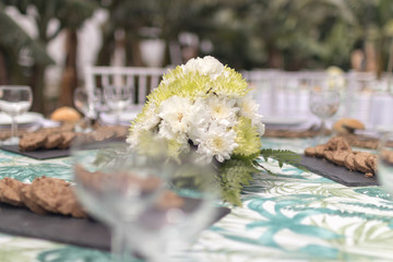 Green and white flower bouquet on tropical decorated table
