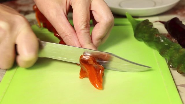 A woman slices churchkhela with walnuts on a chopping Board. Close up.