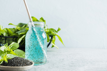 Blue cocktail with basil seeds and tropical juice in glass on light. 