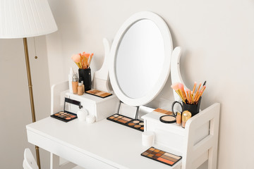 Table with decorative cosmetics and mirror in modern makeup room