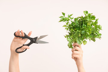 Woman cutting fresh parsley on light background