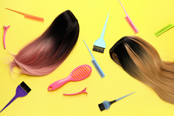 Unusual wigs with hairdresser supplies on color background