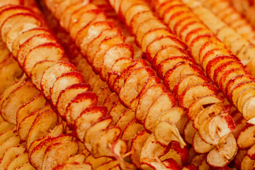 Spiral potato chips with black pepper and spices. Spiral-shaped potato chips baked on a grill in a street market
