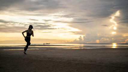 Side view of woman jogging on beach in the morning.