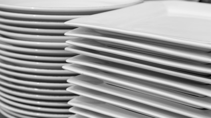 Stack of clean white round and square restaurant dishes.