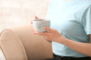 Woman drinking hot coffee at home, closeup