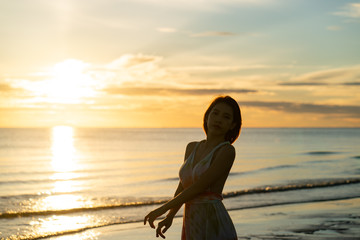 Woman and sunrise shot over the sea with beautiful cloud, sun disappeared behind a big cloud over ocean.
