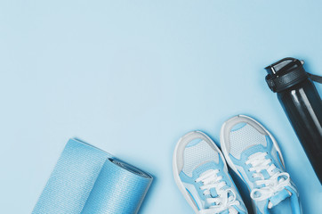 Yoga mat, sport shoes, bottle of water on blue background. Healthy lifestyle