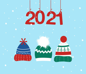 Fototapeta na wymiar Knitted headwear collection,cosy scandinavian winter hats and caps.Happy New Year 2021 and Christmas postcard.Numbers are hanging on ribbons, it is snowing.Childish accessory with pom poms,snowflakes