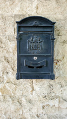 Old mailbox on the wall. Vintage mailbox with antique embossed emblem closeup on rough stone wall background with copy space