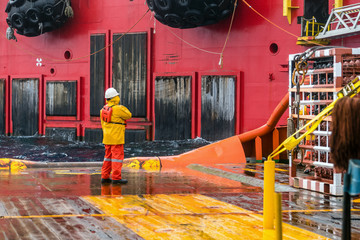 An Able-bodied seamen on anchor handling tug boat prep for receiveing material from a work barge for pipeline installation at Exxonmobil oil field. - obrazy, fototapety, plakaty